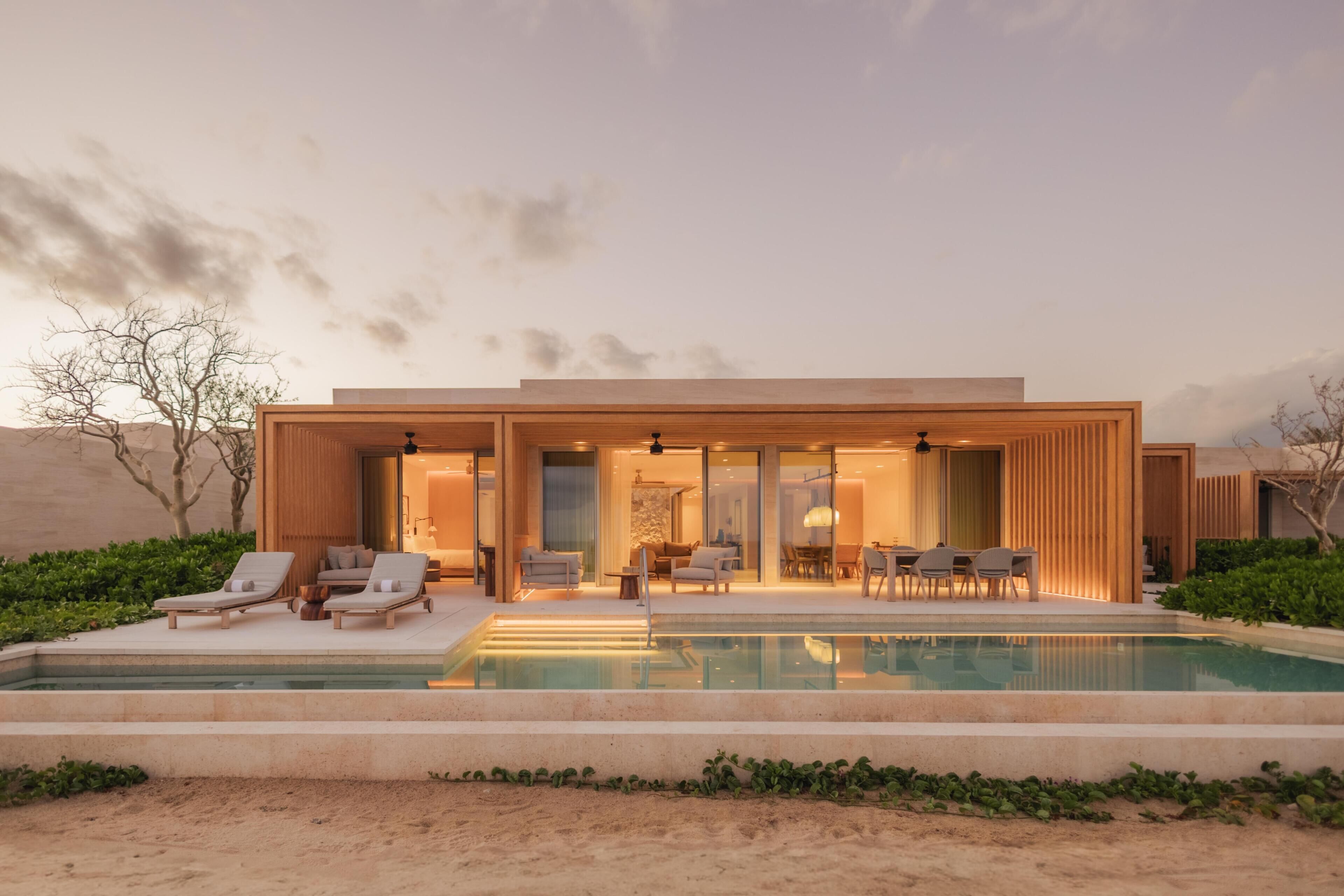 A modern house with a swimming pool, outdoor seating, and a desert landscape.