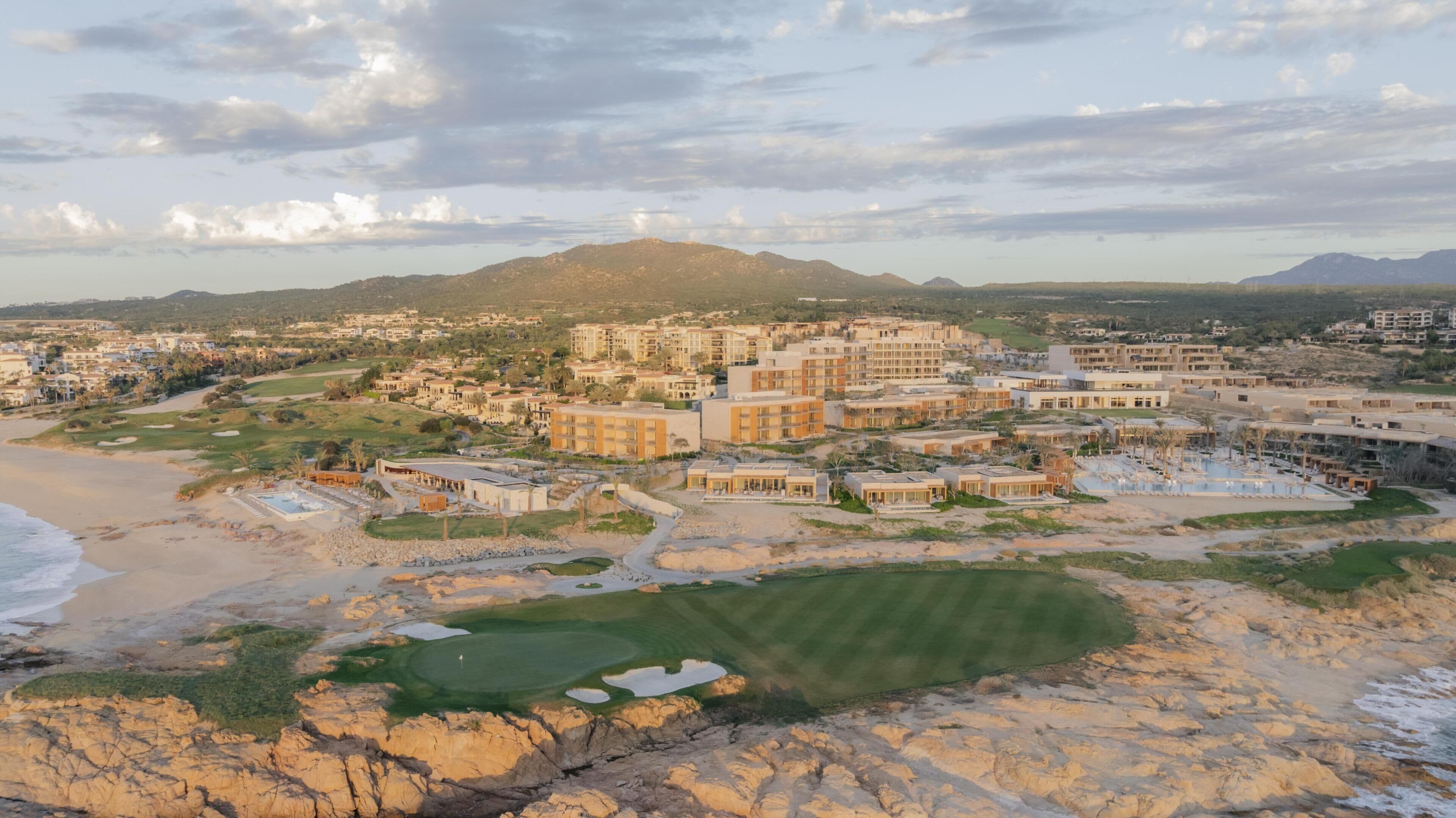 A coastal resort with multiple buildings, a beach, and a golf course.
