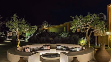 An outdoor seating area with a circular arrangement of sofas and a central fire feature.