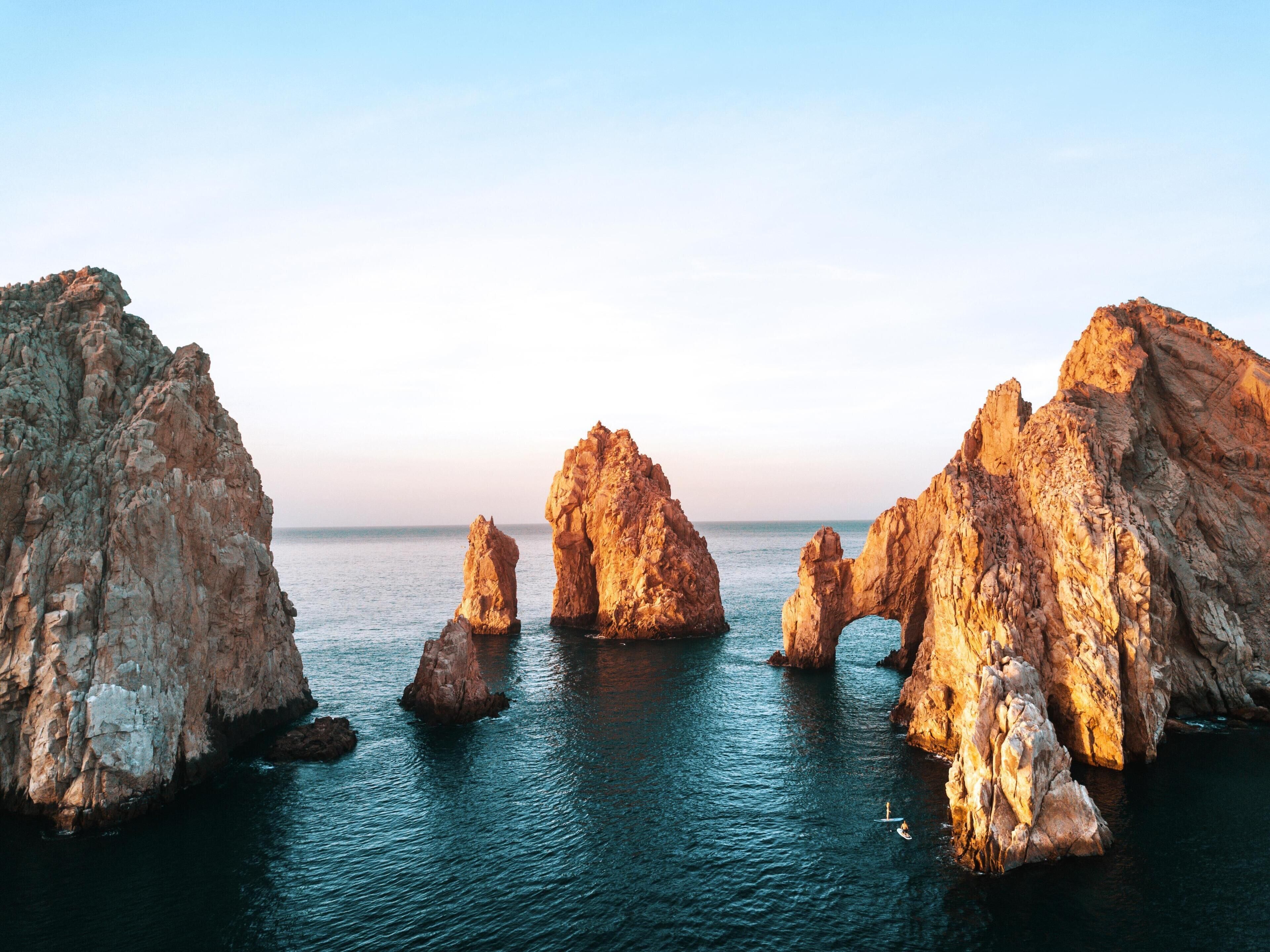 Un paisaje costero con grandes formaciones rocosas y mar tranquilo.