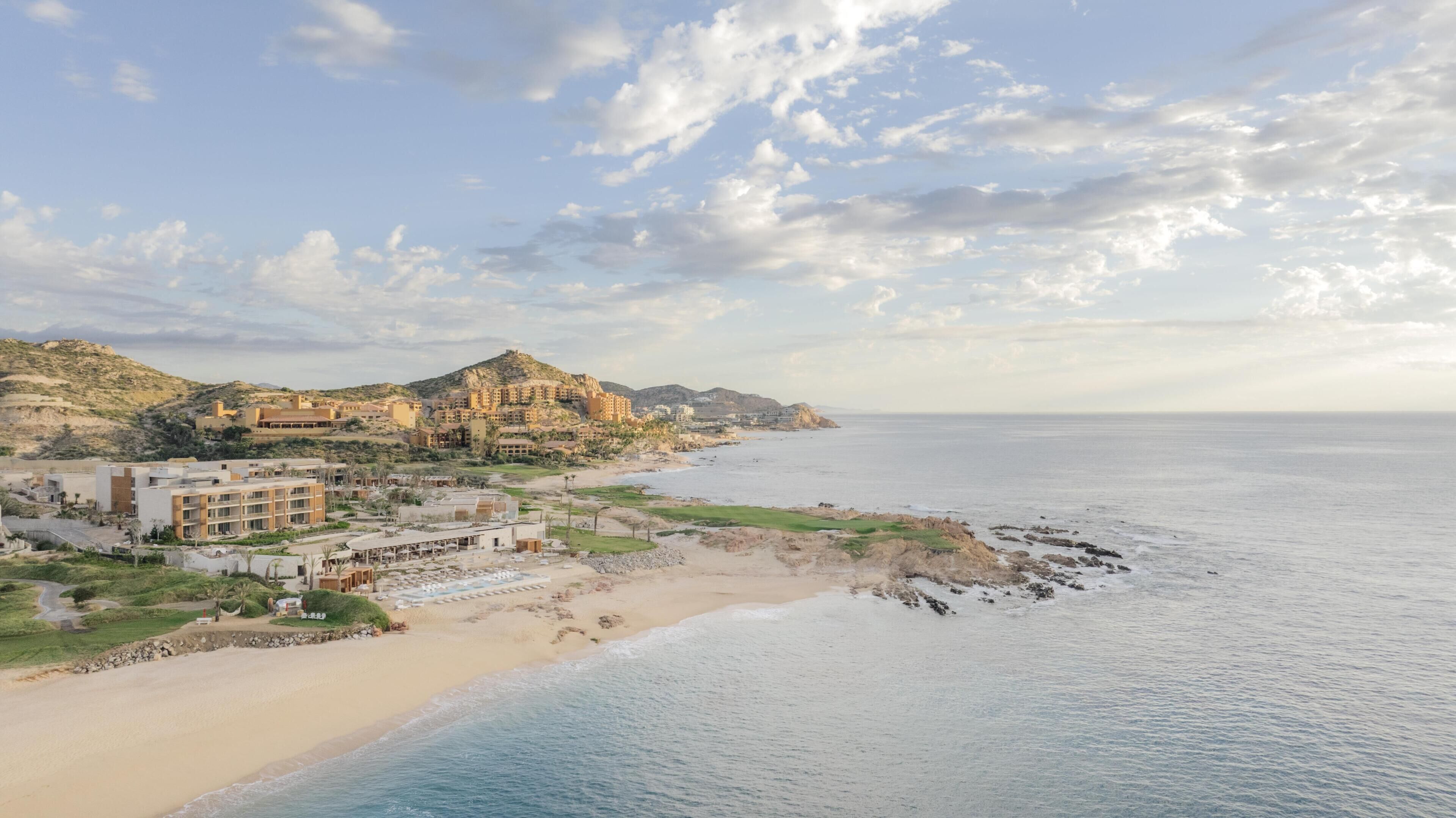 A coastal resort with beachfront villas, a sandy beach, and a view of the sea.
