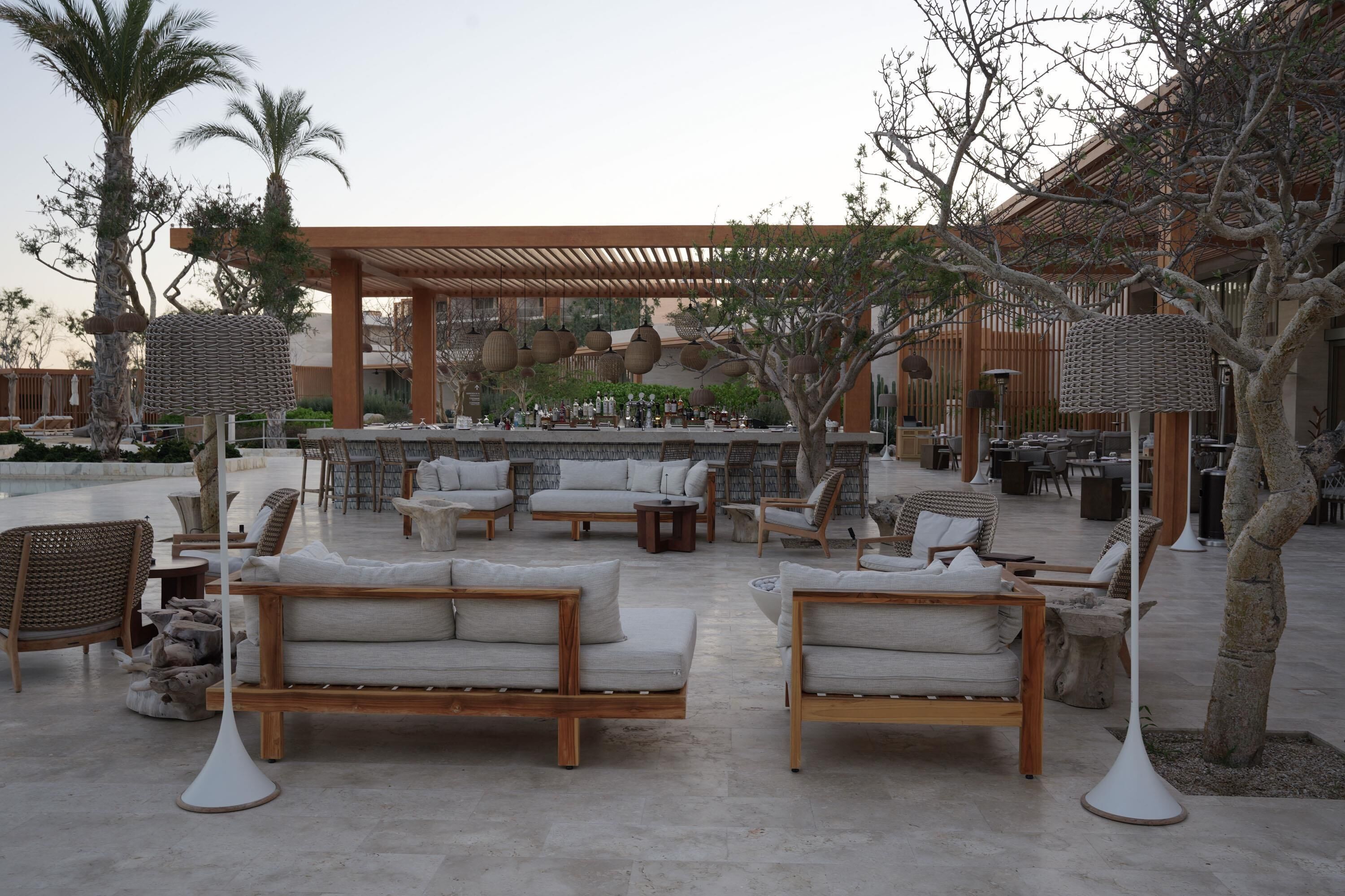 An outdoor seating area with sofas and tables, a bar, and a pergola.