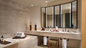 A modern bathroom with a large mirror, a bathtub, and a vanity with a sink.