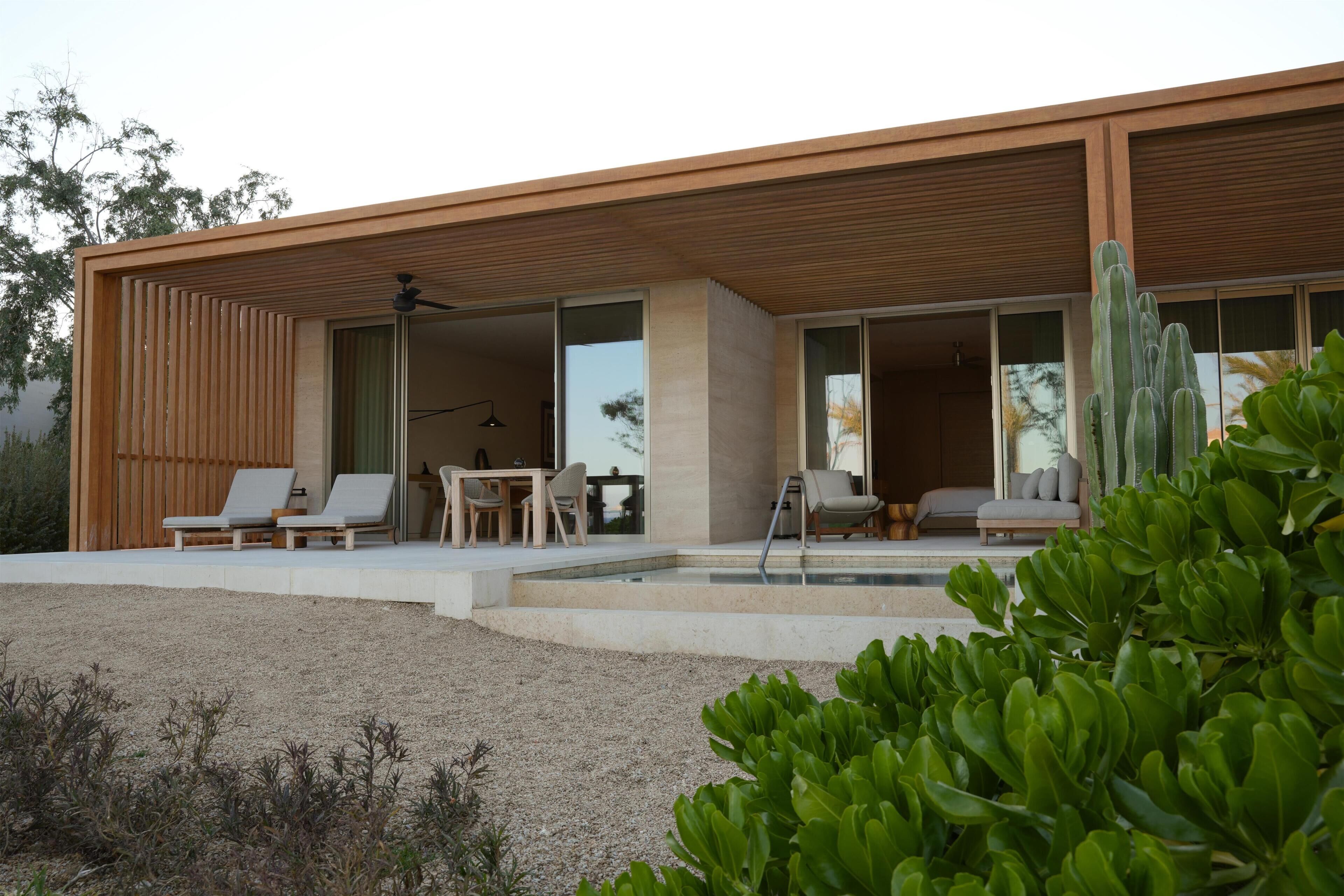 Et moderne hus med terrasse, udendørs møbler og en swimmingpool.