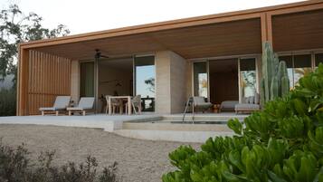 A modern house with a patio area, outdoor seating, and a pool.