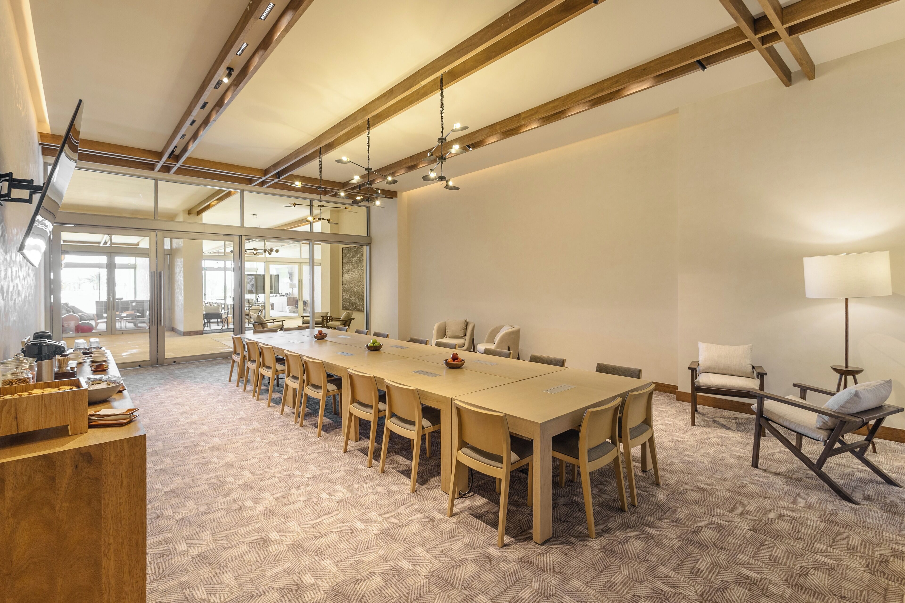 Un salón de conferencias con una mesa larga, sillas y una zona de bufé.