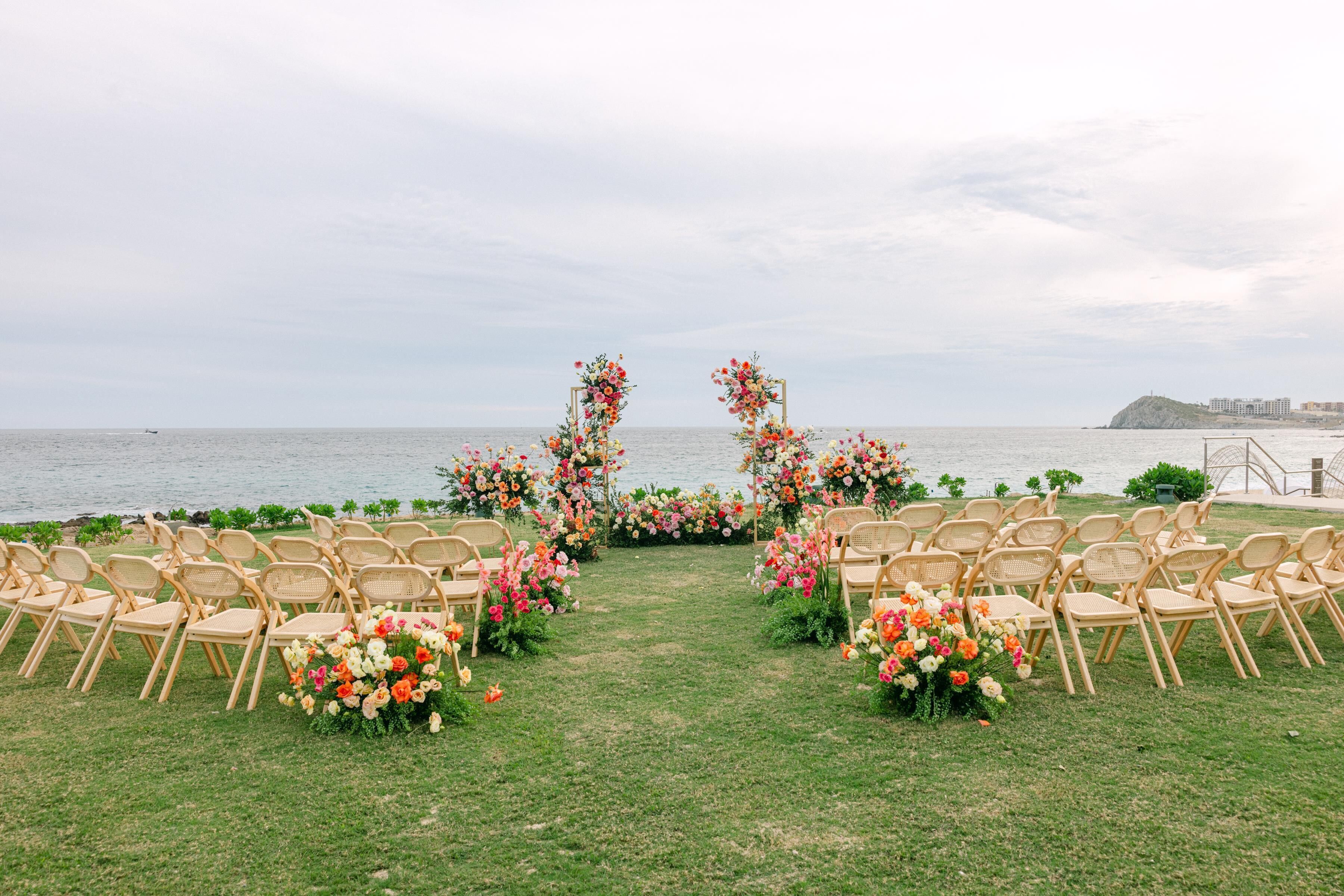 Une cérémonie de mariage en plein air, avec des chaises disposées en rangées face à une arche décorée de fleurs.