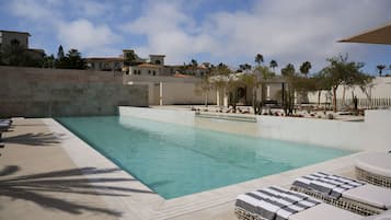 A swimming pool with lounge chairs and palm trees.