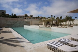 Una piscina con sillas de descanso y palmeras.