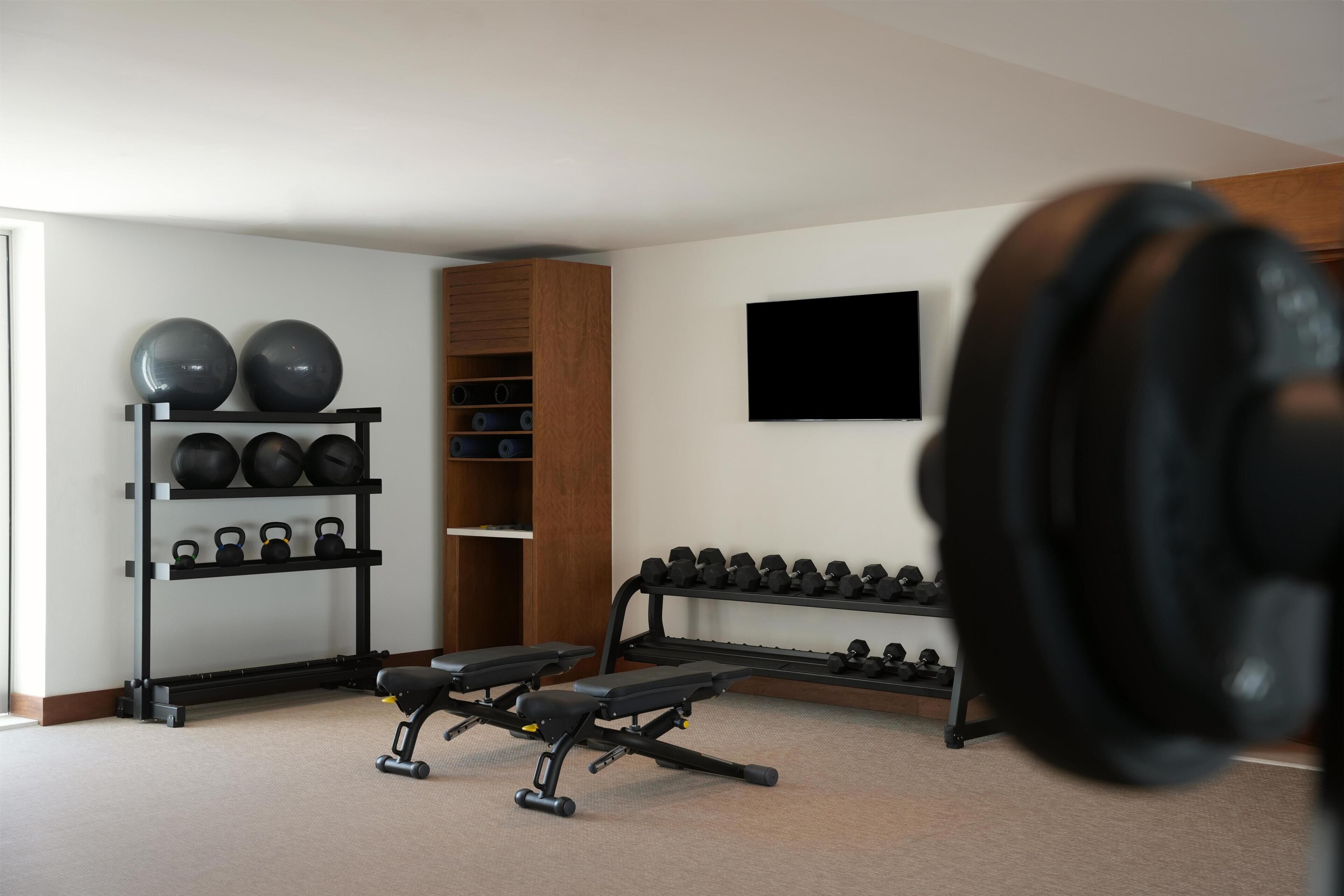A home gym with exercise equipment including kettlebells, a bench, and dumbbells.