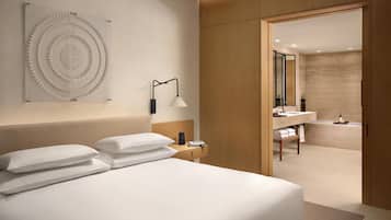 Una habitación de hotel moderna con una cama, una lámpara de pared y vistas al baño.