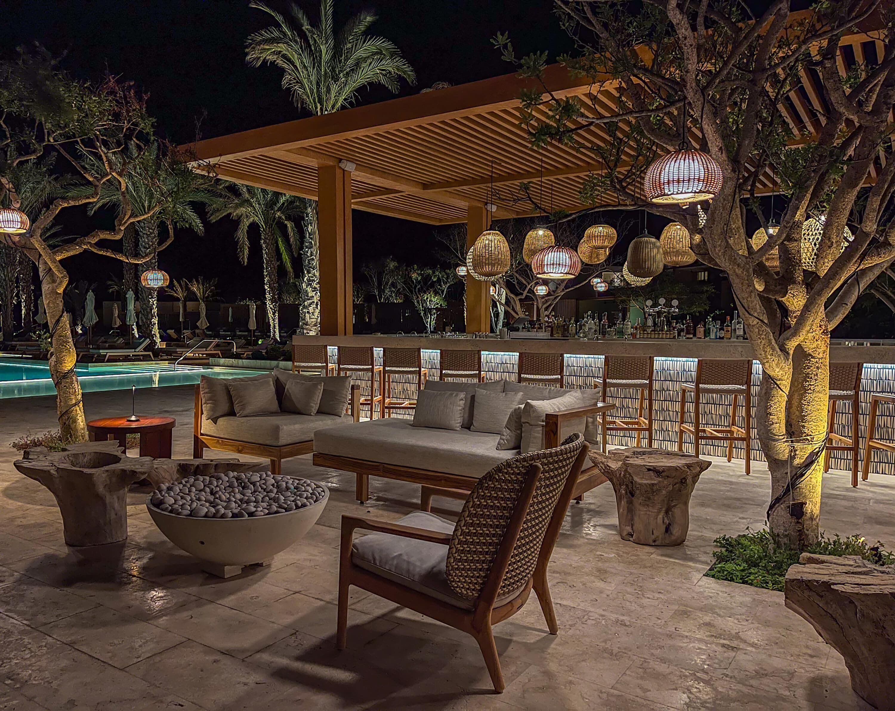 An outdoor lounge area with seating, a pool, and decorative lighting.