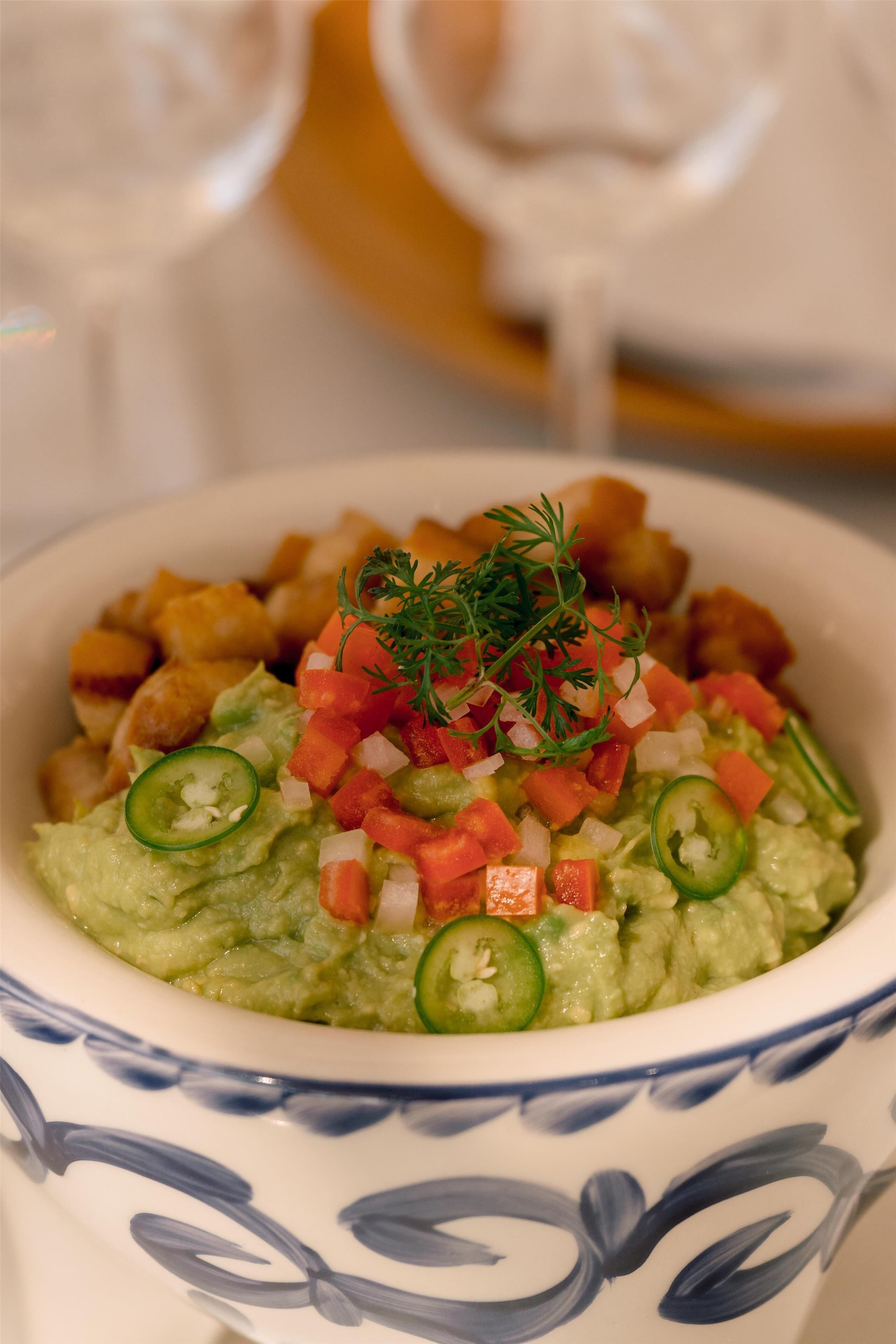 Eine Schüssel Guacamole mit gewürfelten Tomaten, Zwiebeln und Jalapeños, garniert mit Petersilie.