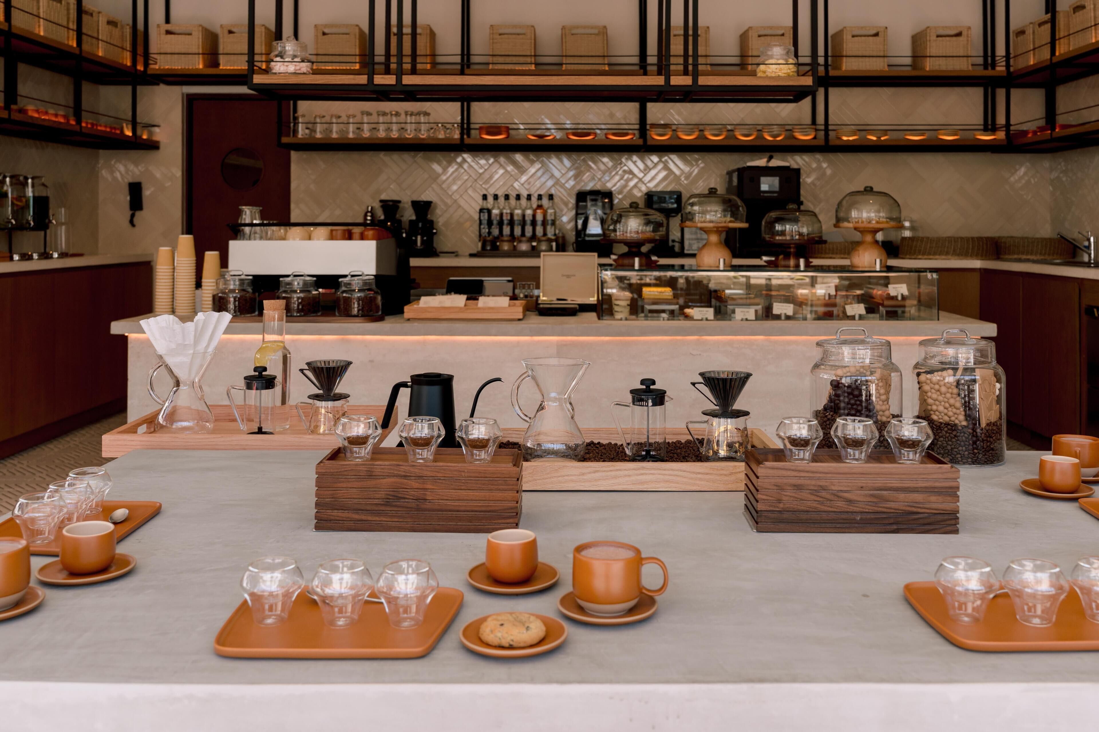 A coffee bar with multiple brewing stations, coffee beans, and a variety of coffee cups and saucers.