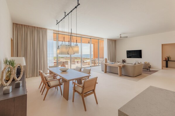 Una sala de estar moderna con comedor, ventanas amplias y un televisor de pantalla plana.