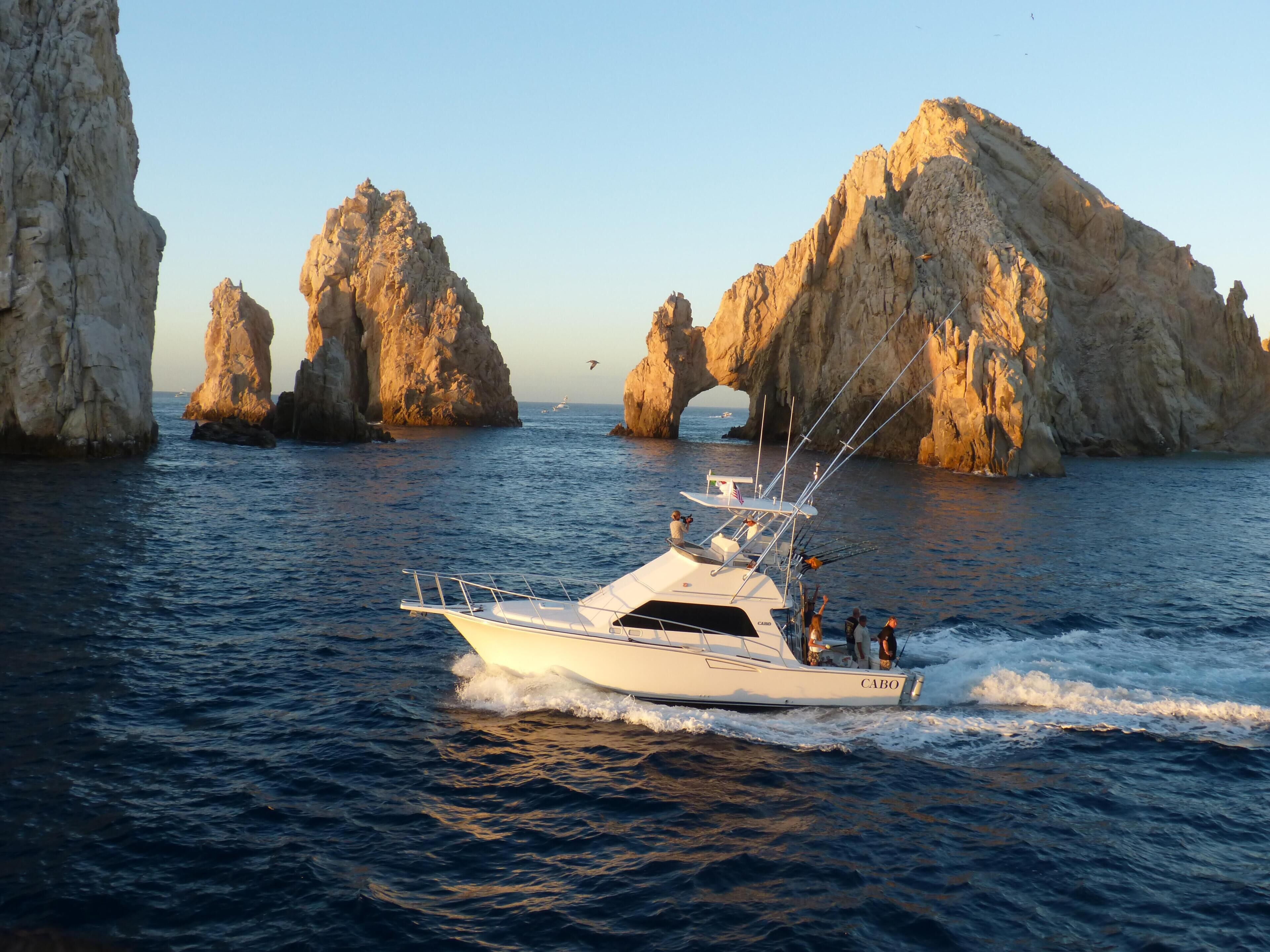 A yacht navigating through a rocky coastal area with large rock formations and a clear sky.