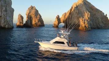 A yacht navigating through a rocky coastal area with large rock formations and a clear sky.