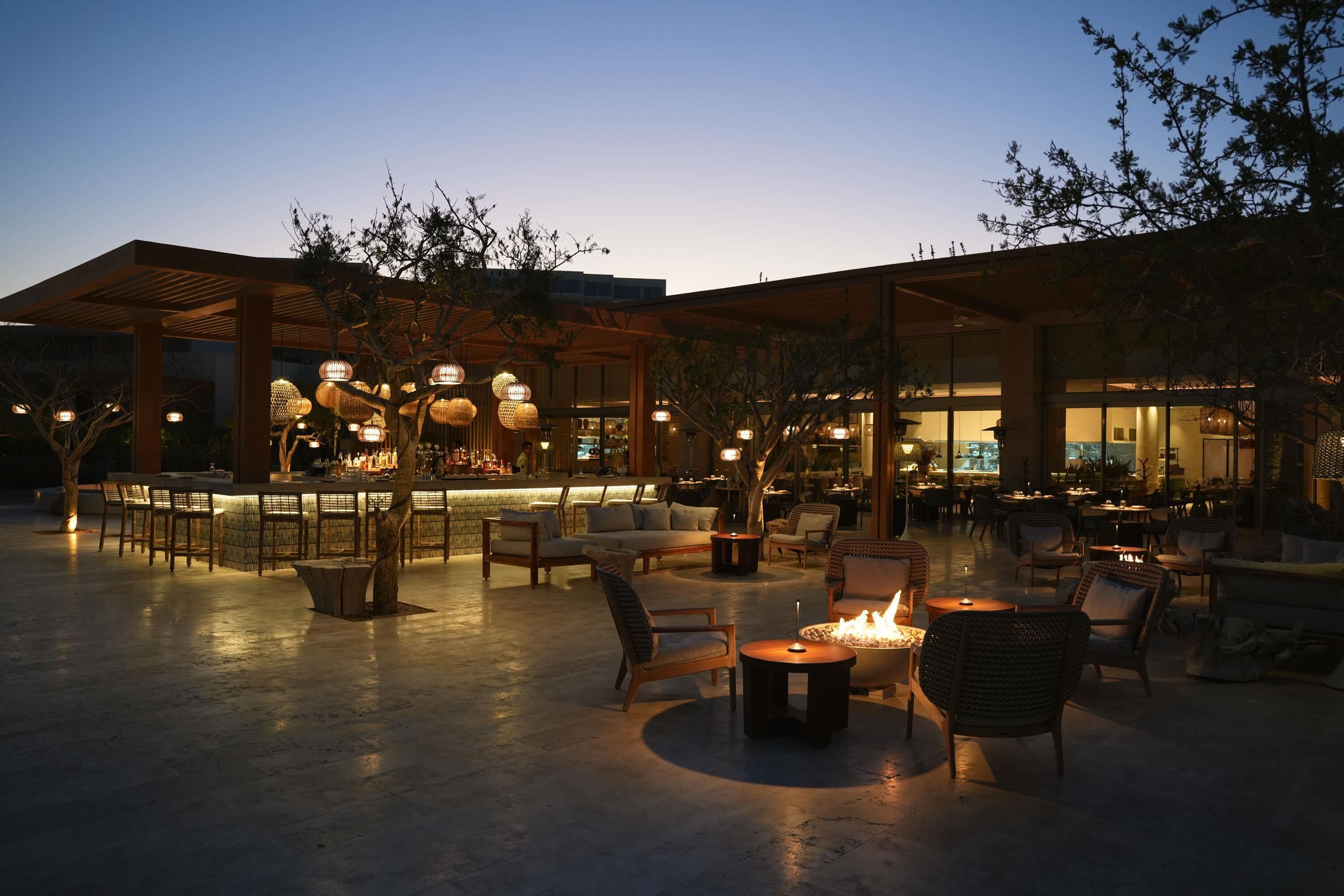 An outdoor seating area with tables and chairs, a bar, and a fire pit.