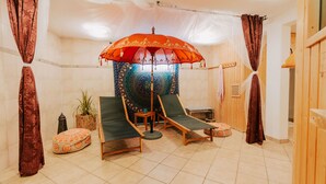 Ein Zimmer mit zwei Lounge-Stühlen, einem gemusterten Sonnenschirm und einem kleinen Tisch.