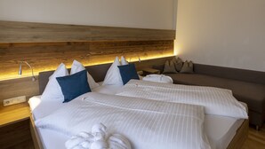 Ein Hotelzimmer mit zwei Betten, einem hölzernen Kopfteil, einem Nachttisch und einem Sofa.
