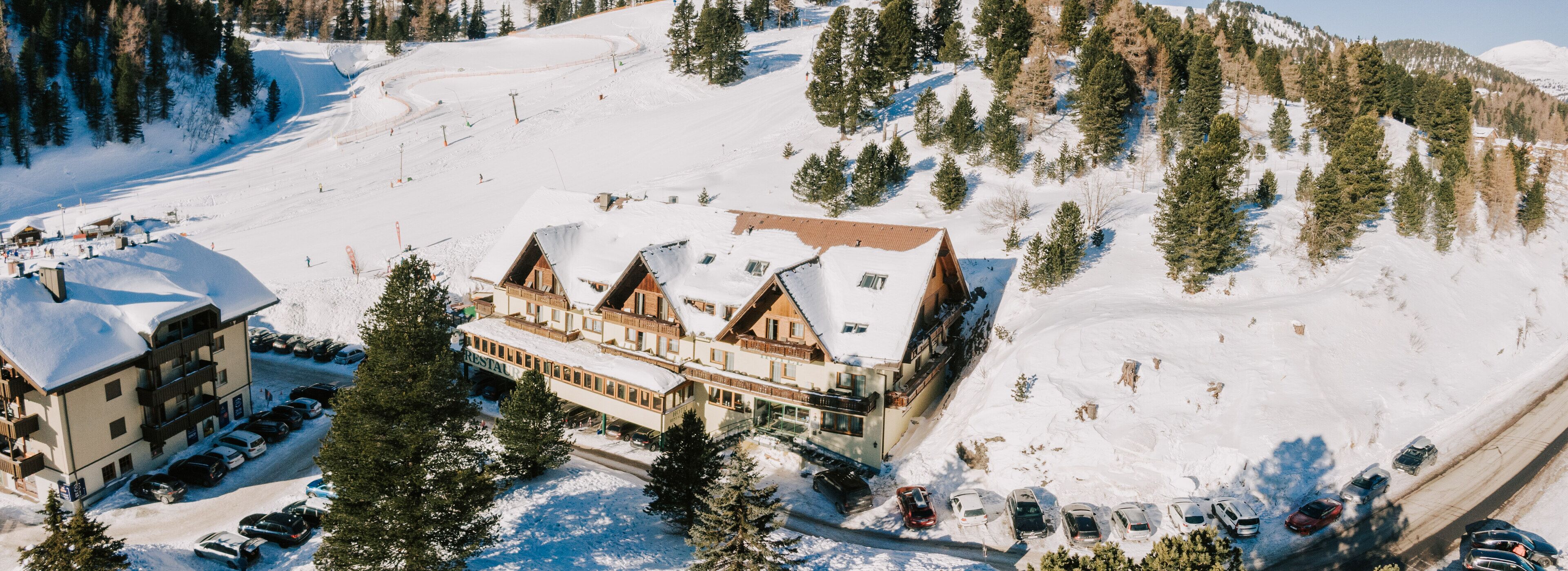 A ski resort with a large lodge, multiple parking areas, and a ski slope.