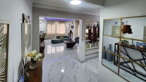 A spacious living area with a marble floor, a sofa, a coffee table, and a bookshelf.