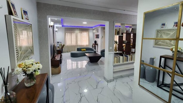 A modern living room with a marble floor, a sofa, a coffee table, and a bookshelf.