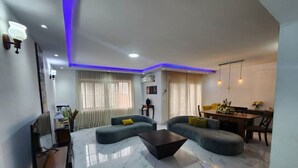 A modern living room with a marble floor, two sofas, a coffee table, and a dining area with a table and chairs.