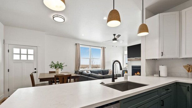 Una cocina moderna con armarios blancos, una isla grande e iluminación colgante.