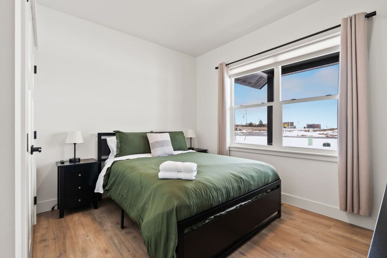 Una camera da letto con un letto, un comodino, una finestra con tende e vista sull'esterno.