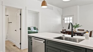 Una cocina moderna con lavavajillas, un lavamanos y una zona de comedor con mesa y sillas.