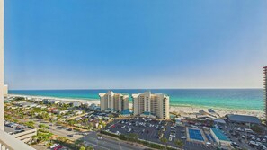 A coastal cityscape with a beach, high-rise buildings, and a parking lot. - Ocean Paradise 1425-Ocean Views-Sleeps 7 (Panama City Beach)