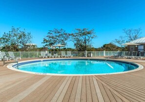 Ein Poolbereich mit Holzterrasse, Liegestühlen und einem eingezäunten Schwimmbecken.