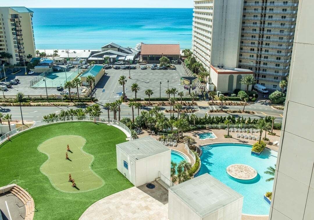 Un resort con piscina, campo de golf y vista al océano.