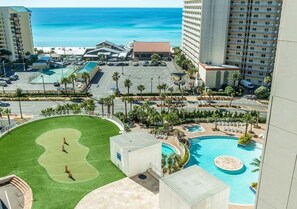 A resort with a pool, a golf course, and a view of the ocean.