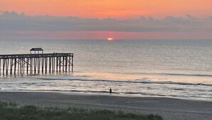 Eine Steg, der sich in ruhiges Wasser erstreckt, mit einem Sonnenuntergang im Hintergrund.