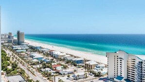 A coastal cityscape with a beach, buildings, and a clear sky. - Ocean Paradise 1425-Ocean Views-Sleeps 7 (Panama City Beach)