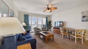 A living room with a sofa, coffee table, TV, and a dining area with chairs and a table. - Ocean Paradise 1425-Ocean Views-Sleeps 7 (Panama City Beach)
