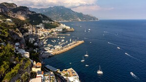 A coastal town with buildings along the cliffside, a marina with boats, and a clear view of the sea. - AMORE RENTALS - Villa Margherita with Sea View and Swimming Pool (Amalfi)