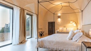 A bedroom with a four-poster bed, a large window with curtains, and a view of the cityscape. - AMORE RENTALS - Villa Margherita with Sea View and Swimming Pool (Amalfi)