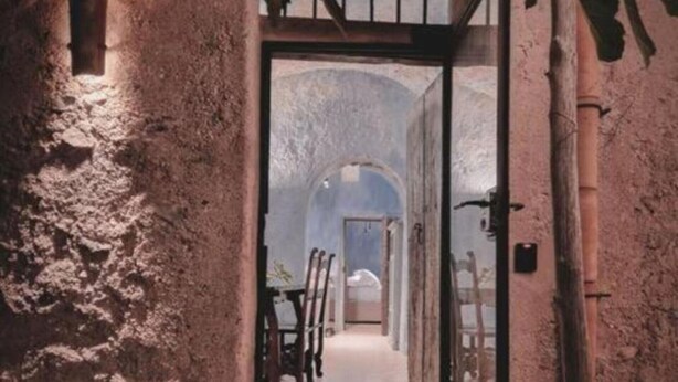 A narrow, rustic hallway with stone walls and a wooden door leading to a room with a bed and a table. - AMORE RENTALS - Villa Margherita with Sea View and Swimming Pool (Amalfi)