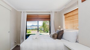 Een slaapkamer met een groot bed, uitzicht op het landschap en een raam met jaloezieën.