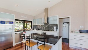 Een moderne keuken met een centraal eiland, roestvrijstalen apparatuur en uitzicht op de omgeving.