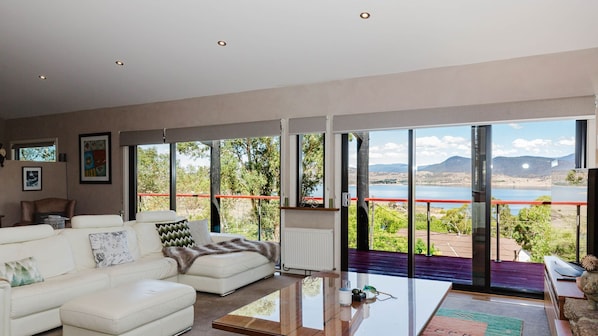 Un salon moderne doté d’une grande porte vitrée donnant sur un balcon avec vue sur le lac.