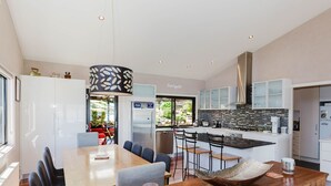 Een moderne keuken met een eethoek, met een groot schiereiland, barstoelen en een centrale kroonluchter.