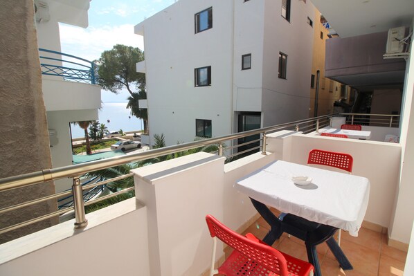 A balcony with a table and chairs, overlooking a pool and buildings. - Elena Hotel (Sarandë)
