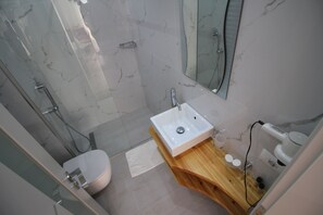 A modern bathroom with a marble shower, a white sink, and a wooden vanity. - Elena Hotel (Sarandë)