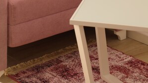 Un canapé rose et une table blanche dans une pièce où se trouve un tapis à motifs.
