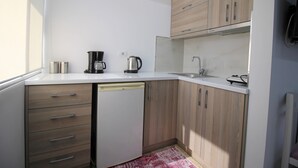 Une cuisine compacte avec des meubles en bois, un plan de travail blanc, une machine à café et un lave-vaisselle.