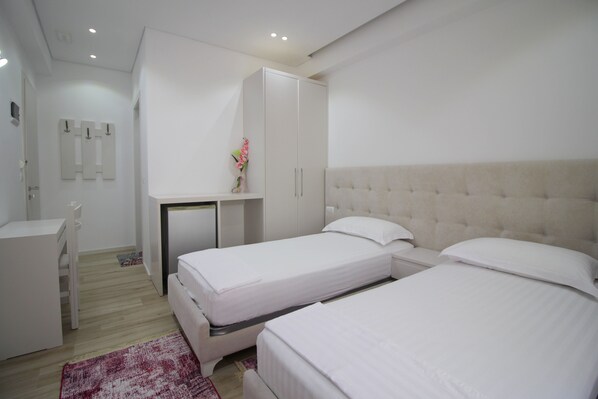 A modern hotel room with two single beds, a desk, and a wardrobe. - Elena Hotel (Sarandë)